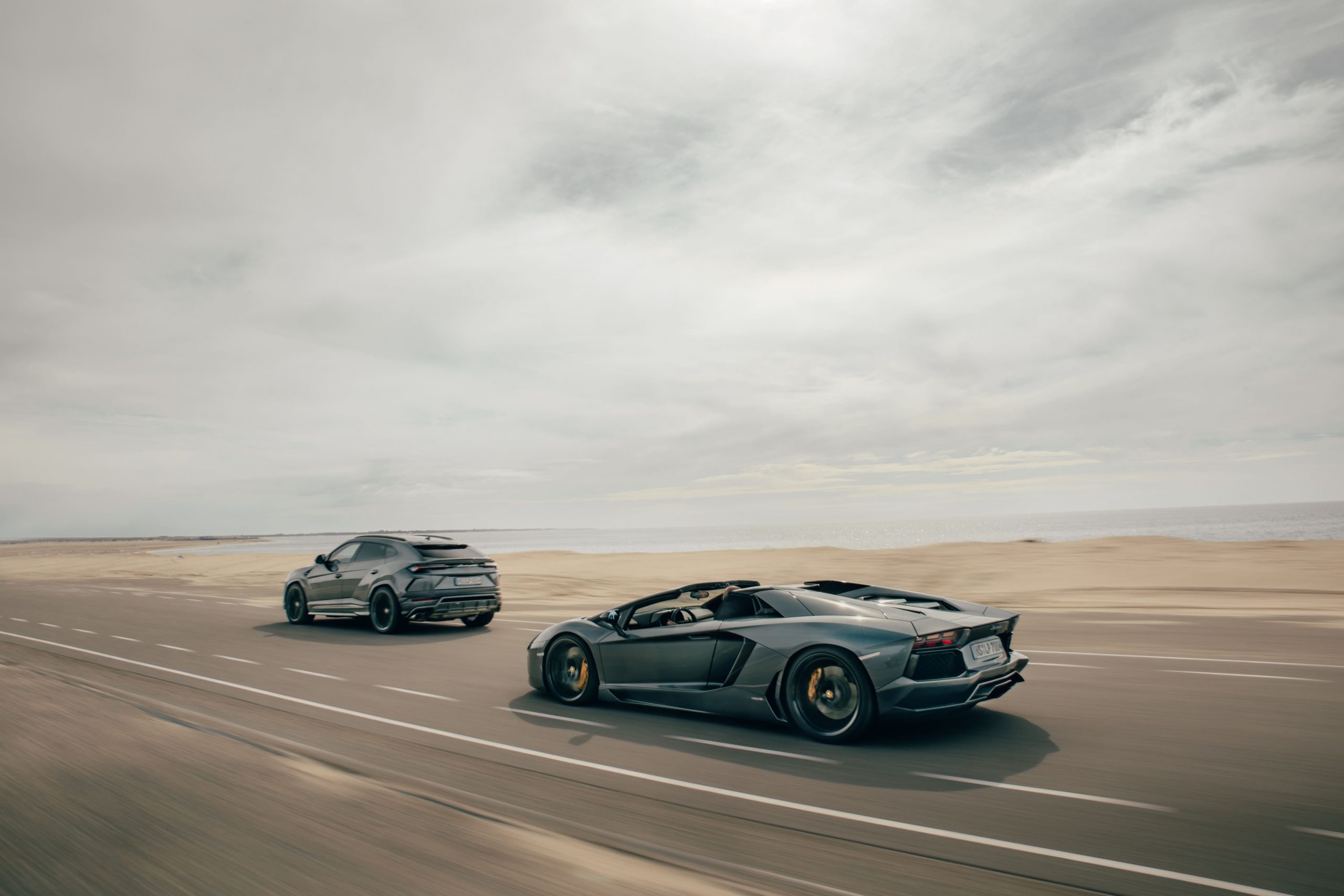Supercars die rijden op een weg die door het zand gaat.